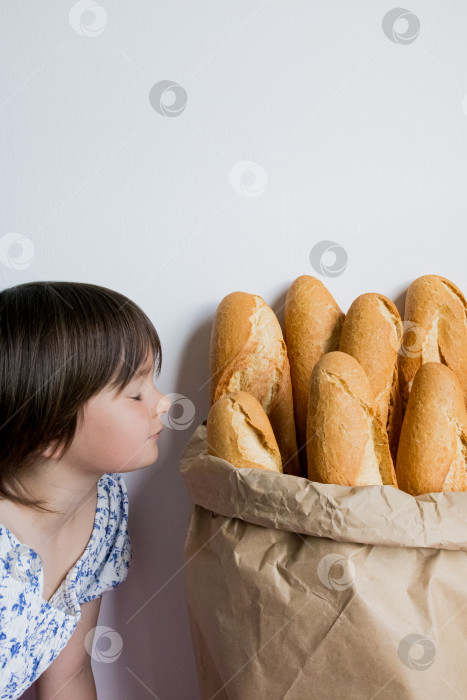 Скачать Молодая кавказская девушка любуется свежими багетами в бумажном пакете фотосток Ozero