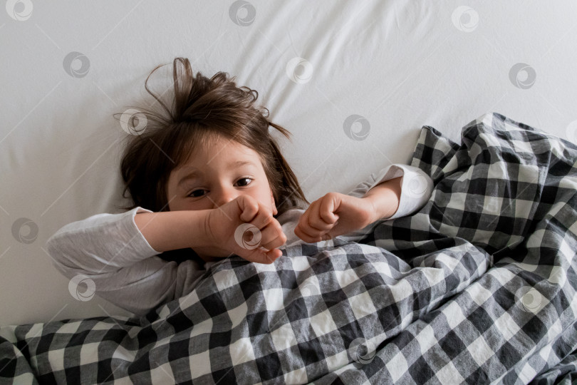 Скачать Уютный кавказский ребенок отдыхает в кроватке с клетчатым одеялом фотосток Ozero