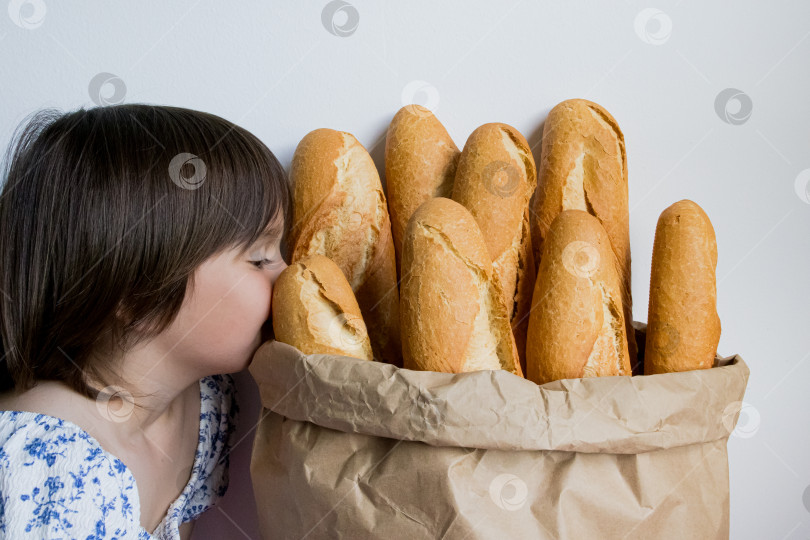 Скачать Молодая девушка наслаждается свежими багетами в бумажном пакете фотосток Ozero