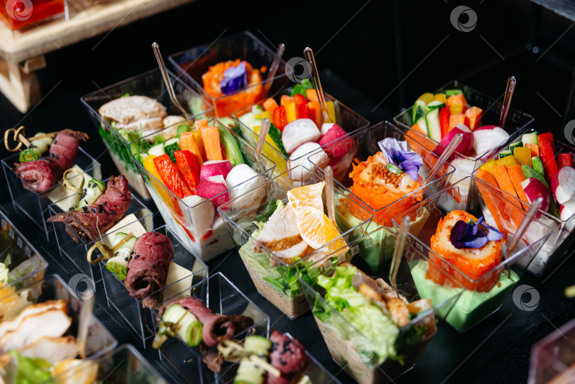 Скачать Ассорти из изысканных салатов и мясных закусок в стаканчиках с овощами. фотосток Ozero