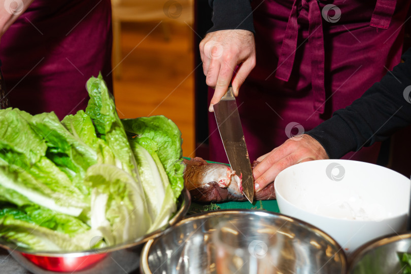 Скачать Шеф-повар режет сырое мясо во время приготовления блюда. фотосток Ozero