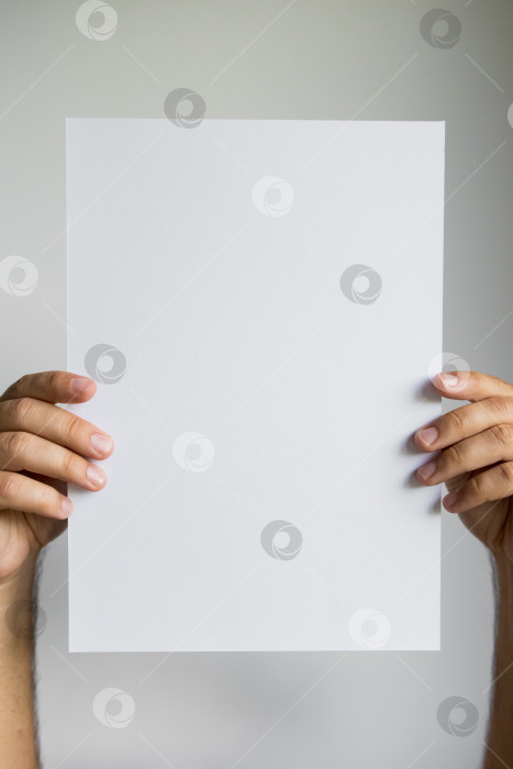 Скачать Руки, держащие чистую белую бумагу на простом фоне фотосток Ozero