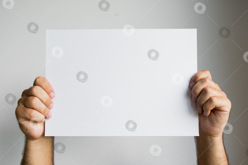 Скачать Руки, держащие чистую белую бумагу на нейтральном фоне фотосток Ozero