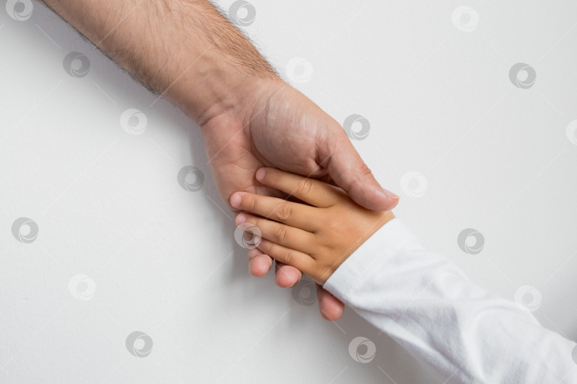 Скачать Взрослый белый мужчина и ребенок-латиноамериканец держатся за руки, выражая связь и доверие фотосток Ozero