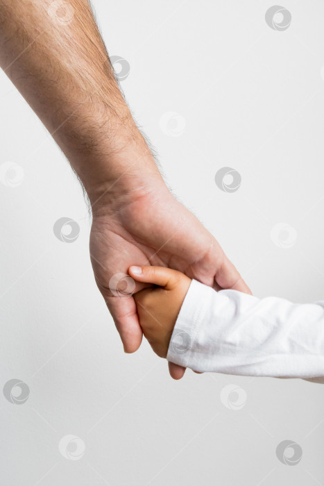 Скачать Взрослый европеец держит за руку испаноязычного ребенка, символизируя заботу и связь фотосток Ozero