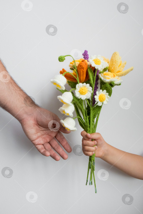 Скачать Ребенок вручает взрослому букет, связанный крючком, демонстрируя яркие цветы ручной работы. Концепция дня отца фотосток Ozero