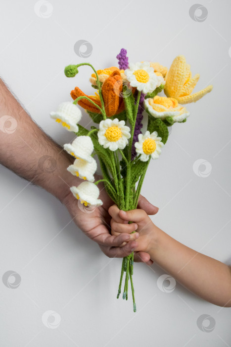 Скачать Детская рука, получающая вязаный букет цветов от взрослого кавказского мужчины. Концепция дня отцов фотосток Ozero