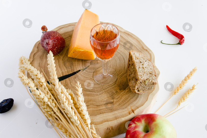 Скачать натюрморт с яблоками и другими продуктами, колосьями пшеницы на дубовой подставке и бокалом домашней крепкой настойки на кедровых орехах фотосток Ozero