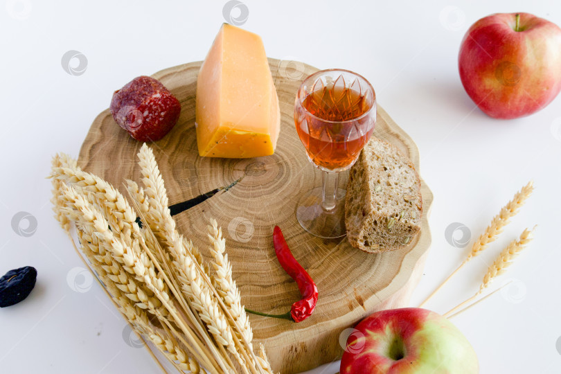 Скачать натюрморт с яблоками и другими продуктами, колосьями пшеницы на дубовой подставке и бокалом домашней крепкой настойки на кедровых орехах фотосток Ozero