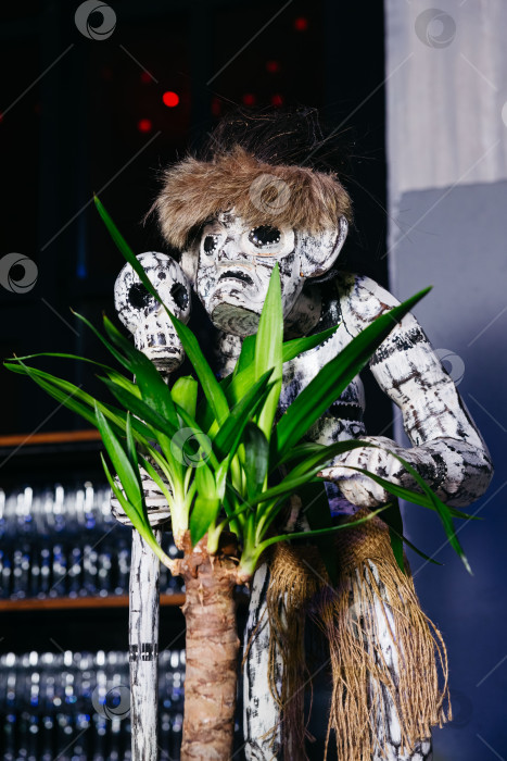 Скачать Деревянная статуэтка в племенном стиле с черепом и растением. фотосток Ozero