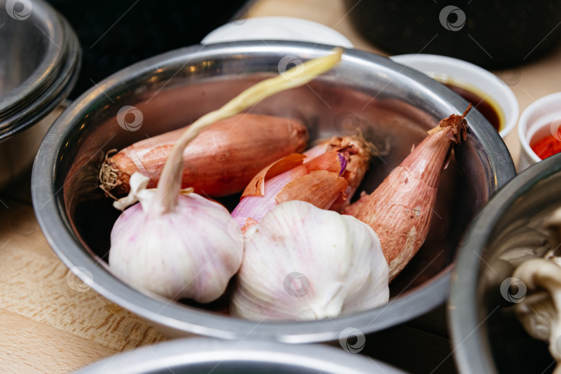 Скачать Положите свежий чеснок и лук-шалот в металлическую миску. фотосток Ozero