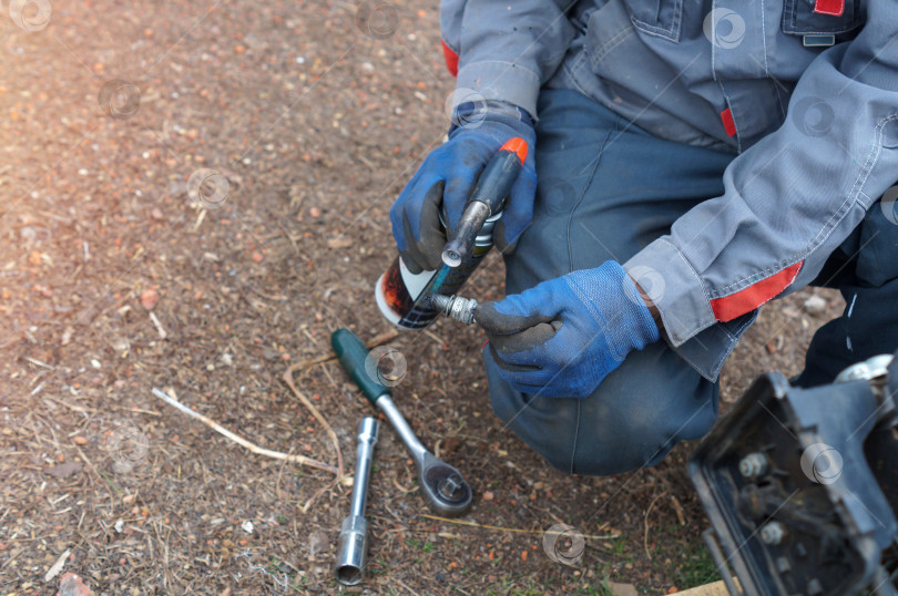 Скачать Быстрая сушка мокрой свечи для мотоблока - работник прокаливает свечку горелкой фотосток Ozero