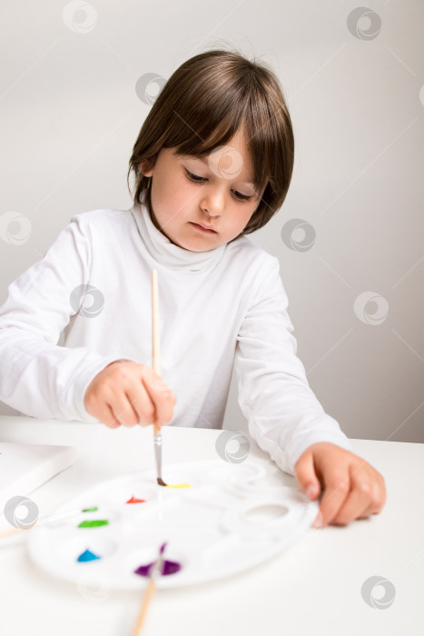 Скачать Молодой кавказский мальчик рисует акварелью на палитре фотосток Ozero