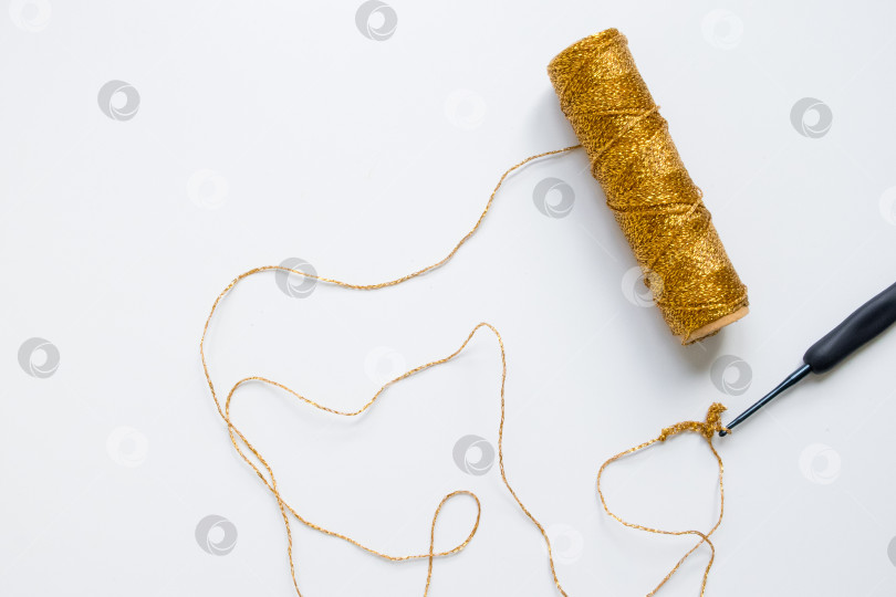 Скачать Моток золотистой пряжи, выполненный крючком на белом фоне. Основы рукоделия и вязания фотосток Ozero