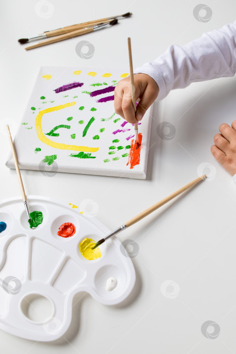 Скачать Ребенок рисует красочное абстрактное искусство на холсте кистями и палитрой фотосток Ozero