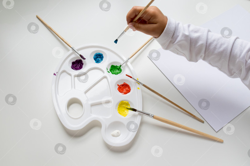 Скачать Детское рисование акварельной палитрой и кистями на белом столе фотосток Ozero