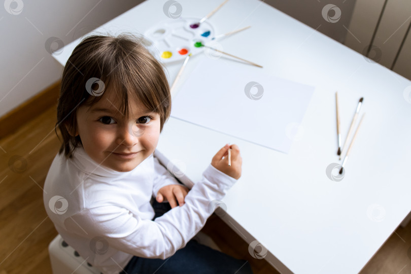 Скачать Маленький кавказский ребенок рисует акварелью на уроке рисования фотосток Ozero