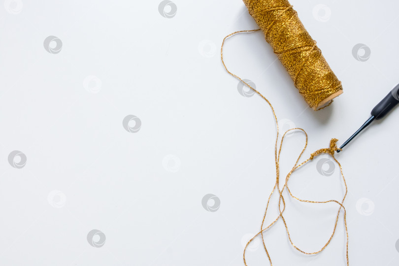 Скачать Золотистая катушка пряжи с крючком для вязания крючком на белом фоне фотосток Ozero