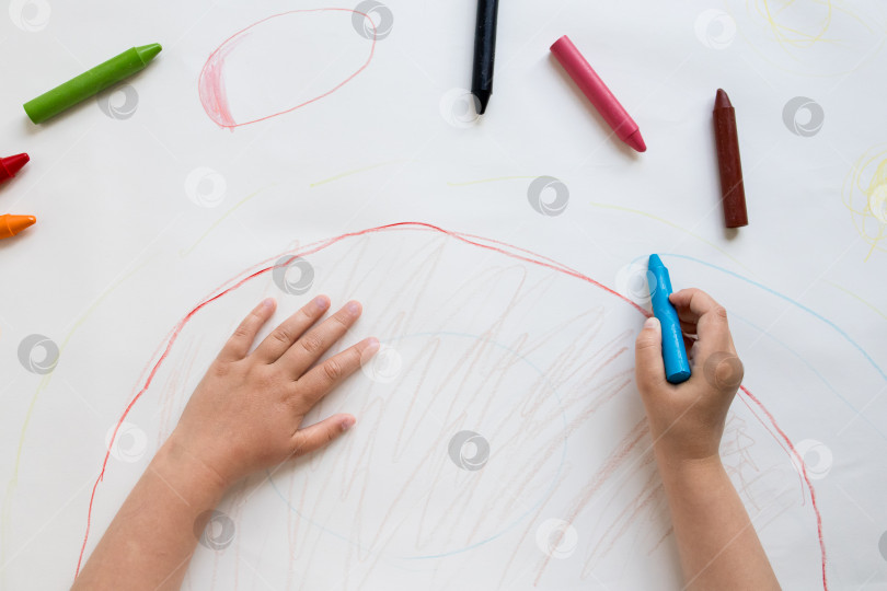 Скачать Ребенок рисует разноцветными мелками на белой бумаге фотосток Ozero
