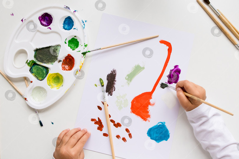 Скачать Ребенок рисует абстрактное искусство красочной палитрой и кистями на белой бумаге фотосток Ozero