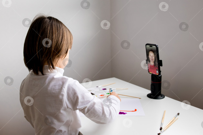 Скачать Молодой кавказский ребенок звонит по видеосвязи, рисуя дома фотосток Ozero