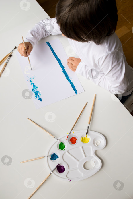 Скачать Маленький кавказский ребенок рисует акварелью дома фотосток Ozero