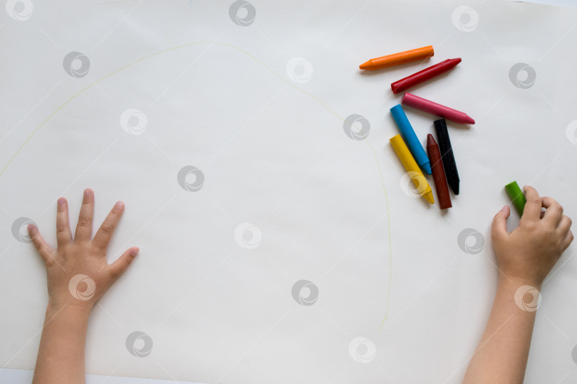 Скачать Ребенок рисует мелками на большой белой бумаге фотосток Ozero