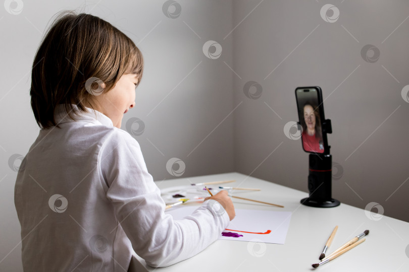 Скачать Молодой кавказский ребенок рисует во время видеозвонка зрелой кавказской женщине фотосток Ozero