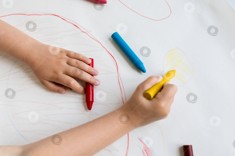 Скачать Ребенок рисует разноцветными мелками на белой бумаге фотосток Ozero