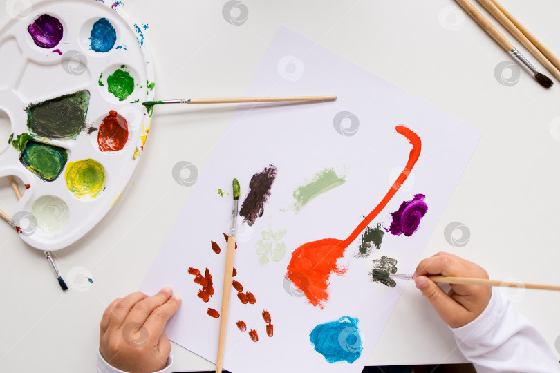 Скачать Ребенок рисует акварелью. Яркие иллюстрации в процессе работы с кистями и палитрой фотосток Ozero