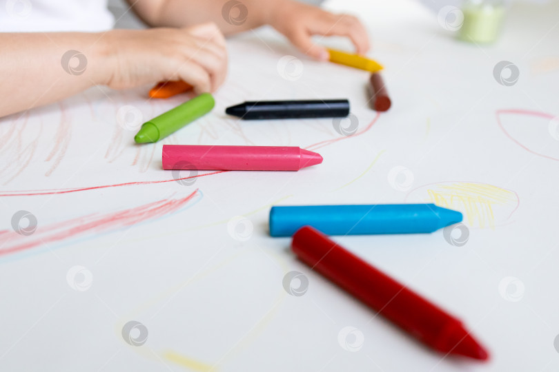 Скачать Ребенок рисует разноцветными мелками на белой бумаге фотосток Ozero