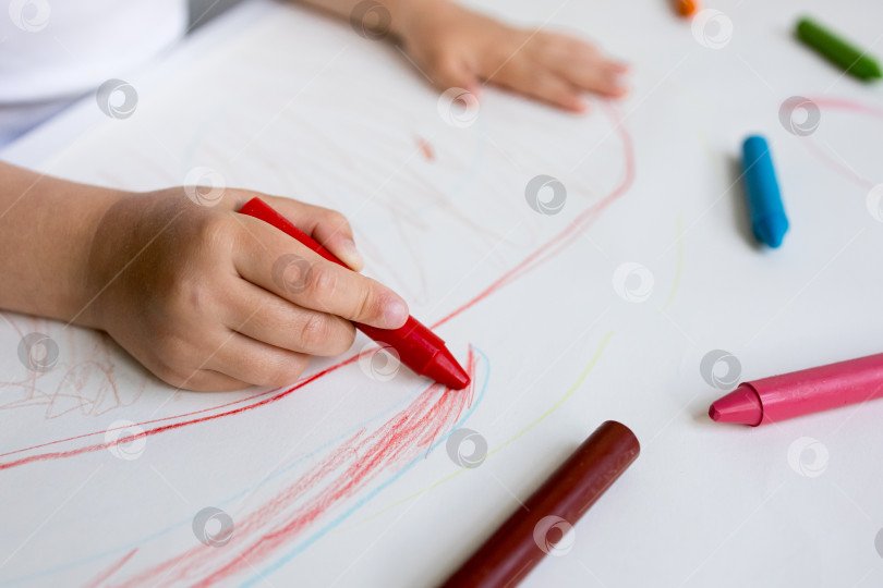 Скачать Ребенок раскрашивает бумагу цветными мелками. Творческое занятие с использованием красных цветных карандашей фотосток Ozero