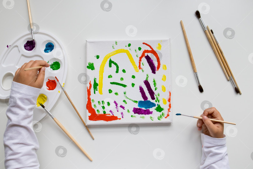 Скачать Ребенок создает красочную абстрактную картину с помощью кистей и палитры фотосток Ozero