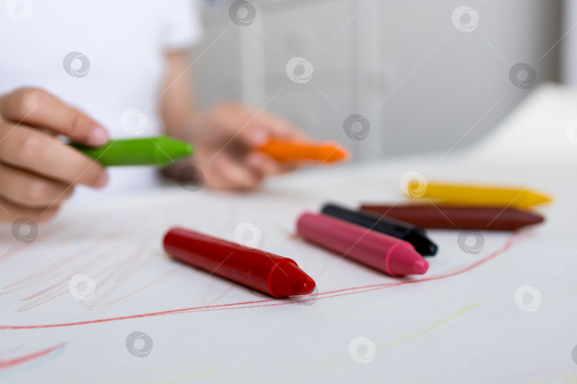 Скачать Ребенок рисует разноцветными мелками на бумаге во время творческой арт-сессии фотосток Ozero