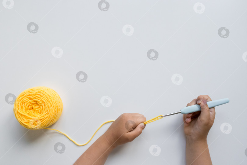 Скачать Детское вязание крючком из желтой пряжи и крючком на белом фоне фотосток Ozero
