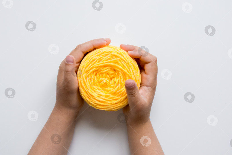 Скачать Детские ручки держат желтую пряжу на белом фоне фотосток Ozero