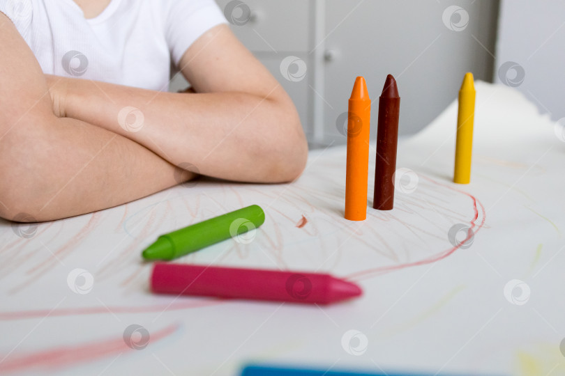 Скачать Ребенок раскрашивает разноцветными мелками за столом фотосток Ozero