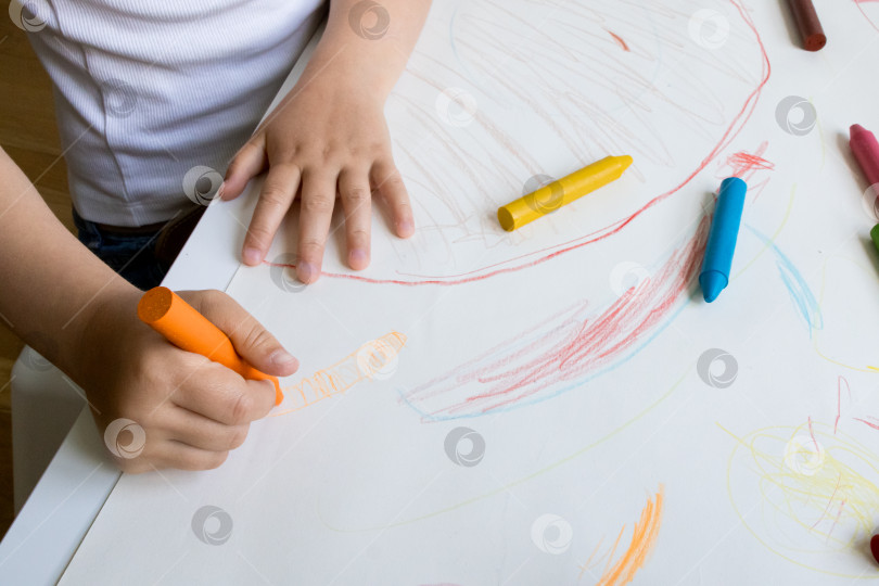 Скачать Ребенок рисует разноцветными мелками на бумаге фотосток Ozero