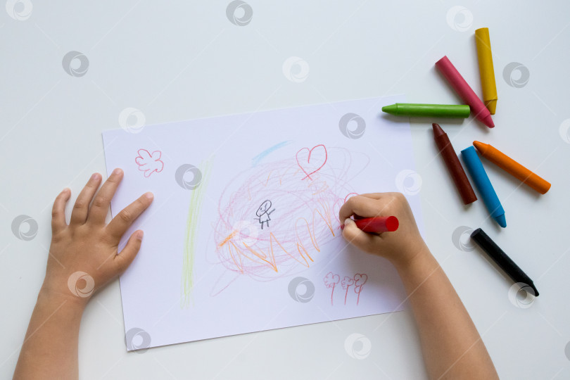 Скачать Ребенок рисует мелками на белой бумаге фотосток Ozero