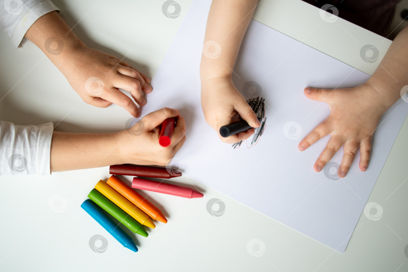 Скачать Дети рисуют разноцветными мелками на белой бумажной поверхности фотосток Ozero