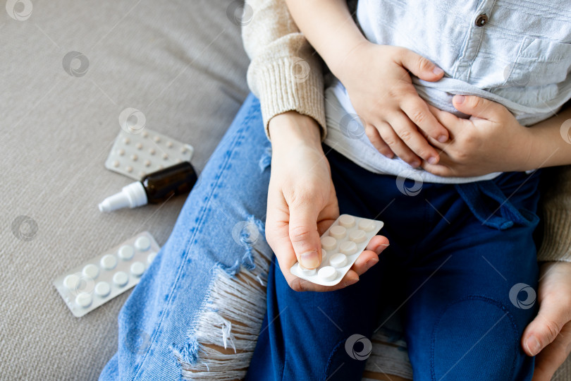 Скачать Взрослая женщина ухаживает за ребенком с лекарствами и комфортом на диване фотосток Ozero