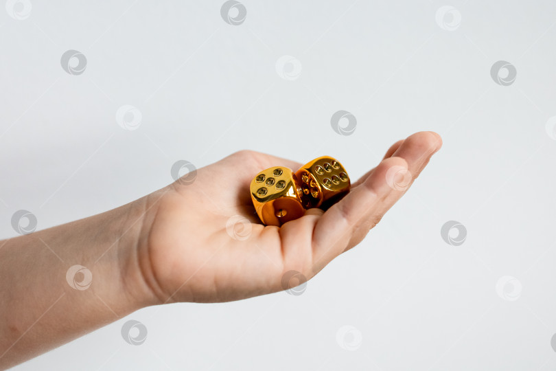 Скачать Рука, держащая золотые металлические игральные кости на белом фоне фотосток Ozero