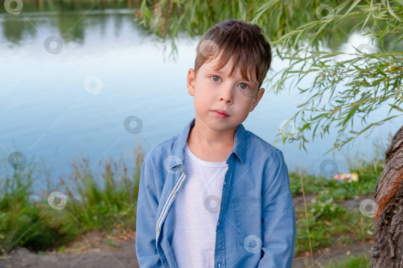 Скачать портрет симпатичного мальчика на фоне озера в парке фотосток Ozero