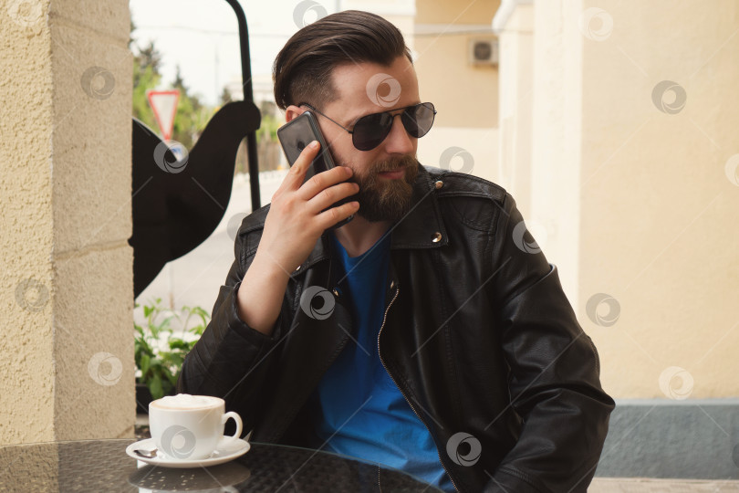 Скачать Модный мужчина на летней террасе кафе со смартфоном фотосток Ozero