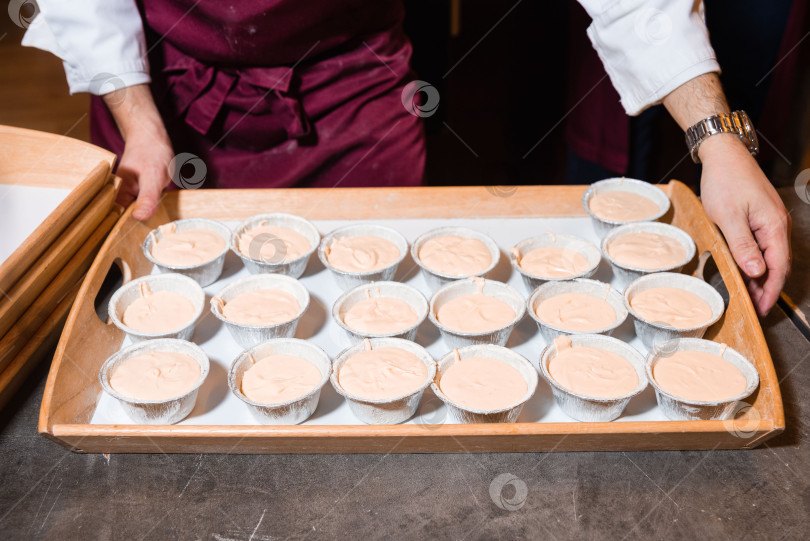 Скачать Шеф-повар готовит поднос с непропеченными кексами. фотосток Ozero