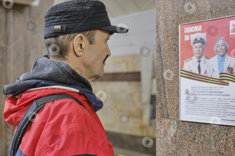 Скачать Мужчина наблюдает за плакатом в честь Дня Победы, посвященным ветеранам войны фотосток Ozero