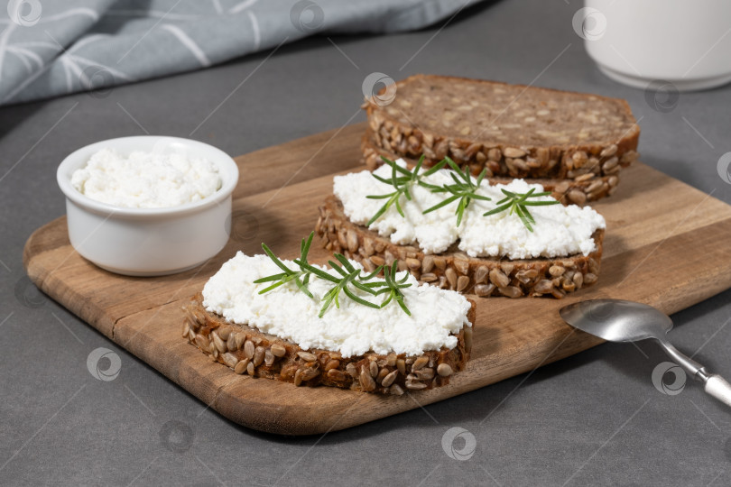 Скачать Вкусный ржаной хлеб со сливочным сыром и свежей зеленью на деревянной доске в деревенском стиле фотосток Ozero