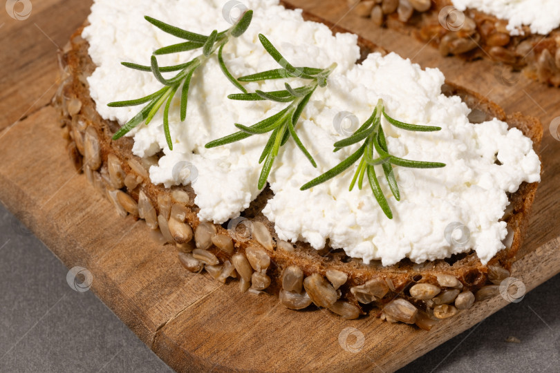 Скачать Вкусный ржаной хлеб со сливочным сыром и свежей зеленью на деревянной доске в деревенском стиле фотосток Ozero