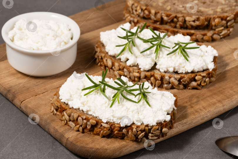 Скачать Вкусный ржаной хлеб со сливочным сыром и свежей зеленью на деревянной доске в деревенском стиле фотосток Ozero