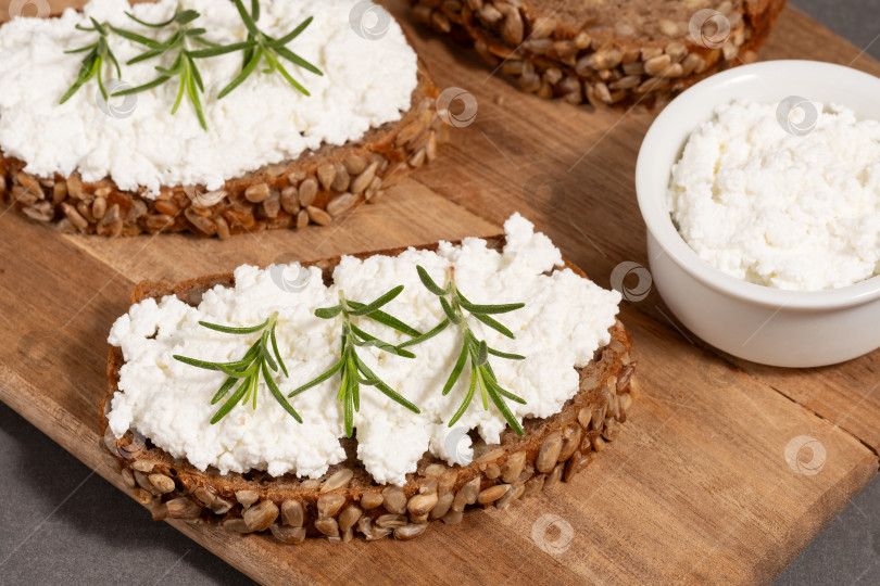 Скачать Вкусный ржаной хлеб со сливочным сыром и свежей зеленью на деревянной доске в деревенском стиле фотосток Ozero